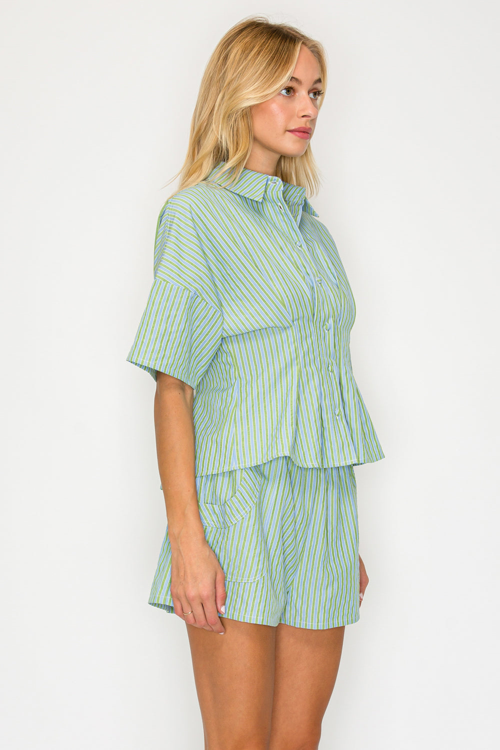 Woman wearing a green and white striped shirt and shorts set on a white background