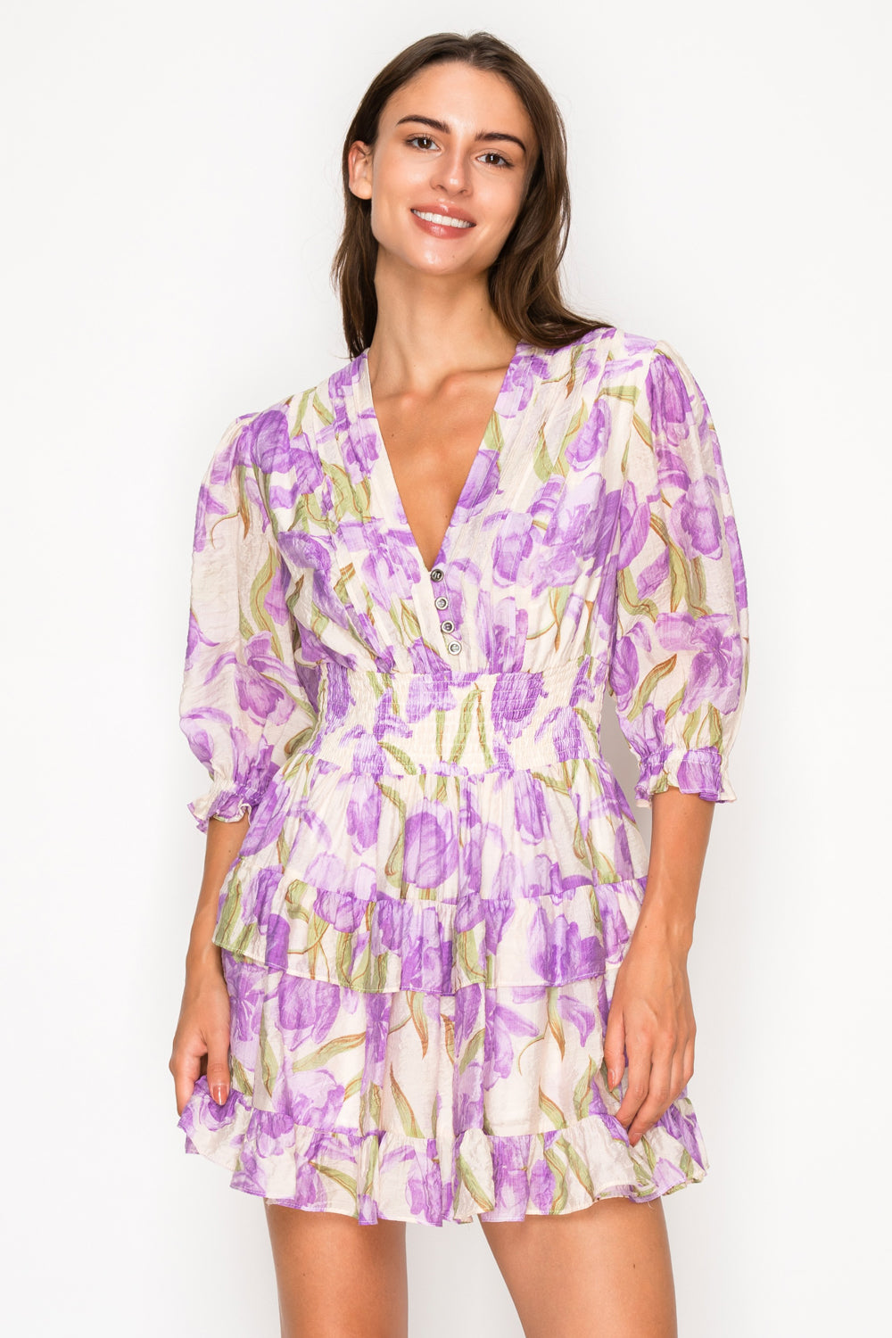 Model wearing the Aphrodites Garden Short Dress, a purple floral print mini dress with a V-neck and puff sleeves.