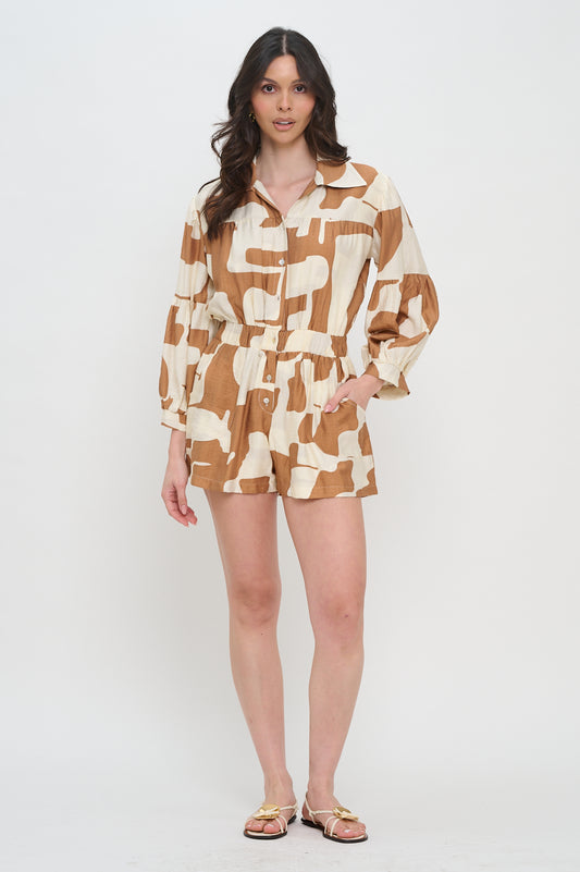 Woman wearing a long sleeve button-down romper with collared neckline, terracotta and cream abstract print, and elastic waist.