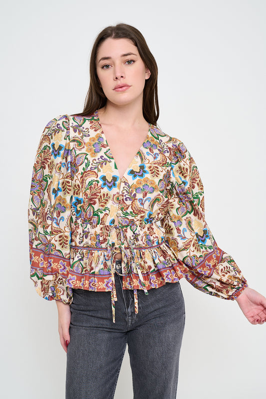 Model wearing printed peplum blouse with long sleeves and V-neckline