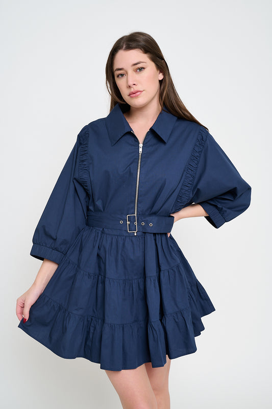 Model wearing a navy poplin mini dress with a zip-up front, belted waist, and tiered skirt.