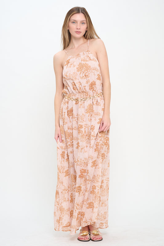 Woman wearing a spaghetti strap maxi dress with a pink and copper pastoral print, metallic accents, elastic waist, and gold chain belt.