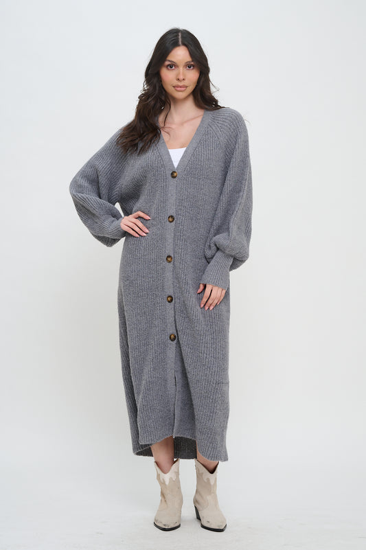 Model wearing the gray Sweater Long Duster, a long knit cardigan with a V-neck, button front, and balloon sleeves.