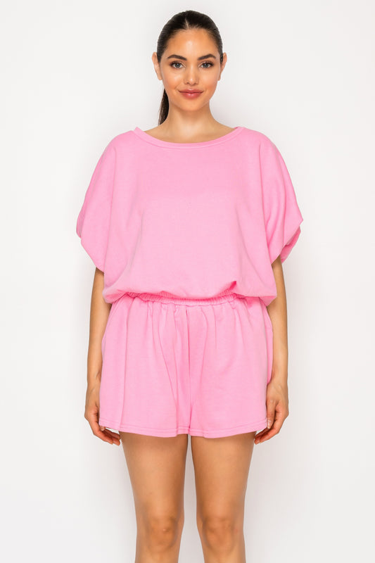 Model wearing the Pink French Terry Set, a two-piece coordinated lounge set featuring a solid pink short-sleeve top and matching elastic-waist shorts.
