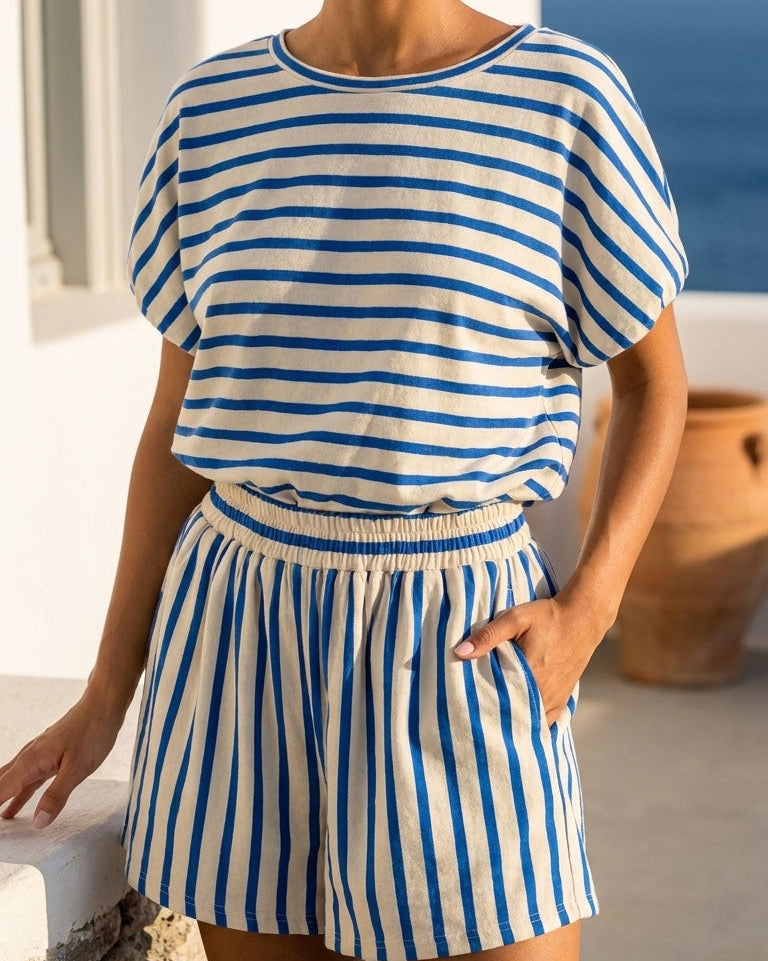 Woman wearing a blue and white striped outfit with a scenic background.