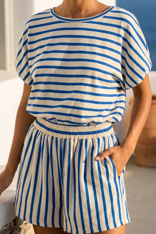 Woman wearing a blue and white striped outfit with a scenic background.