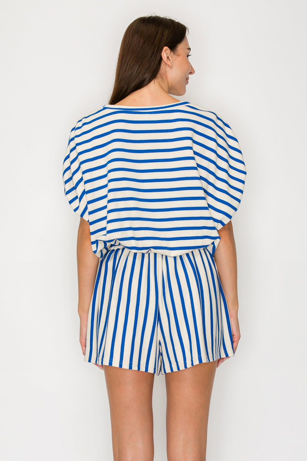 Woman wearing a blue and white striped romper against a plain background