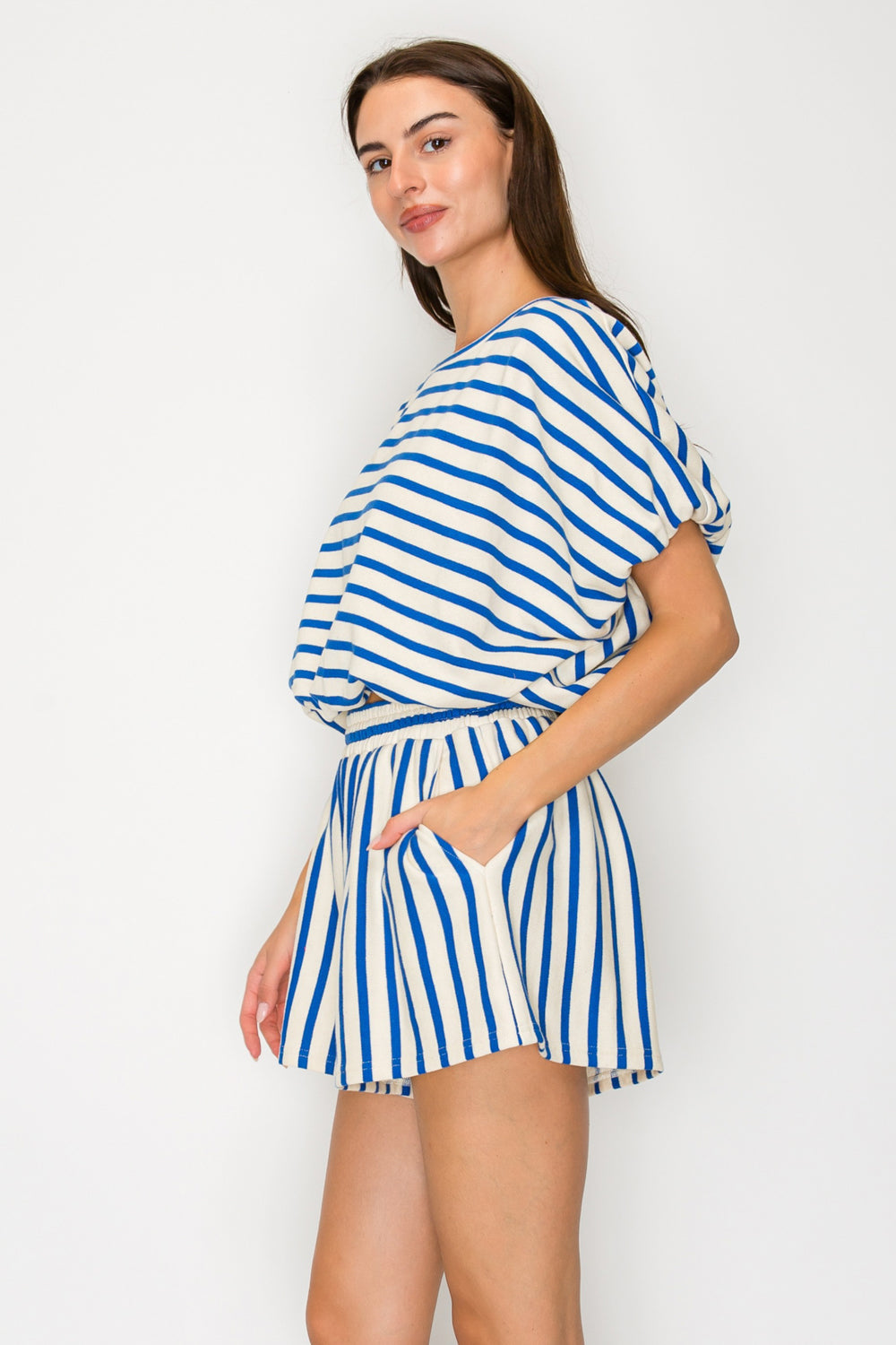 Woman wearing a blue and white striped outfit against a plain background