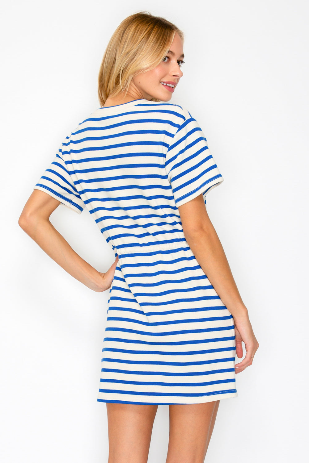 Woman wearing a blue and white striped dress against a plain background