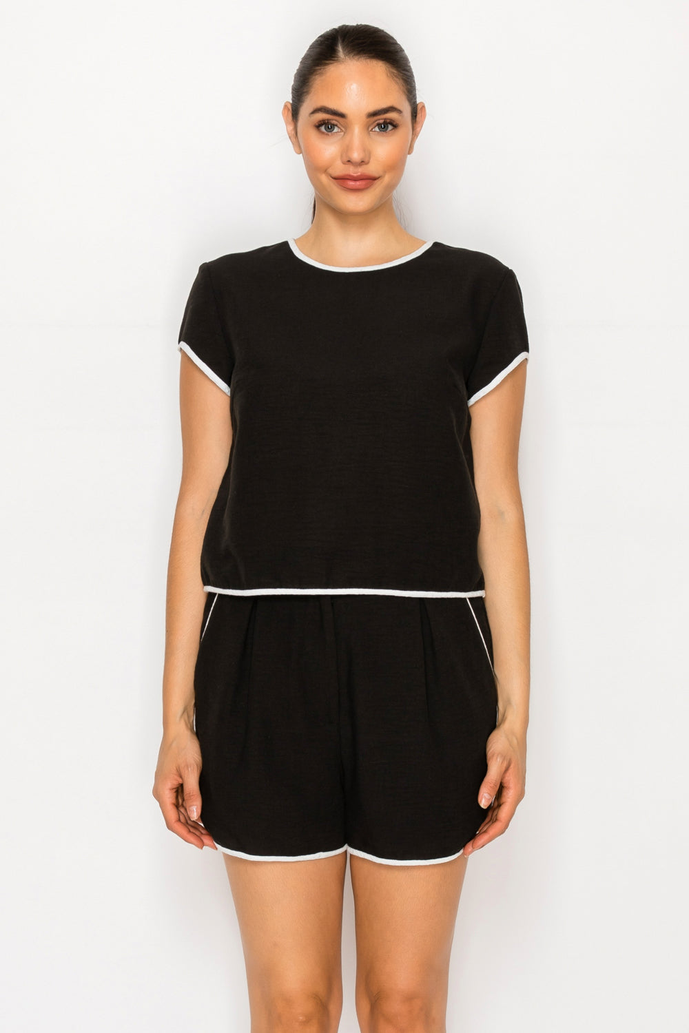 Model wearing the Black White Linen Set, featuring a black short-sleeve top and shorts, both with white piping detail.