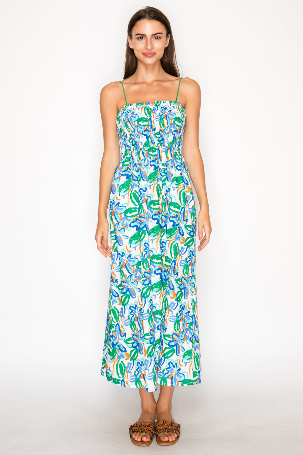 Model wearing the Calista Wild Smock Midi Dress, a white midi dress with a vibrant blue and green abstract floral print, featuring a smocked bodice and thin straps.