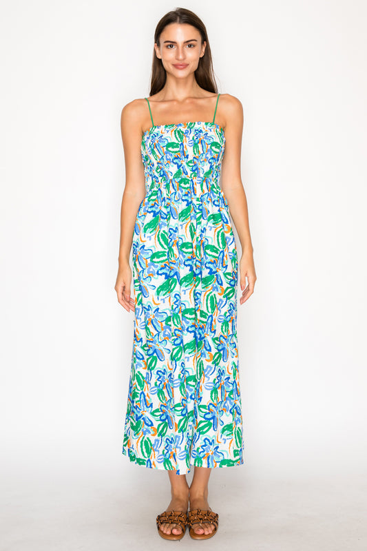 Model wearing the Calista Wild Smock Midi Dress, a white midi dress with a vibrant blue and green abstract floral print, featuring a smocked bodice and thin straps.