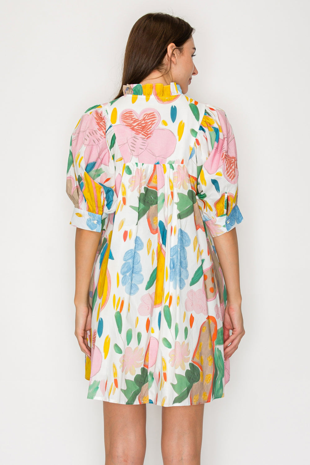 Woman wearing a colorful floral dress against a white background