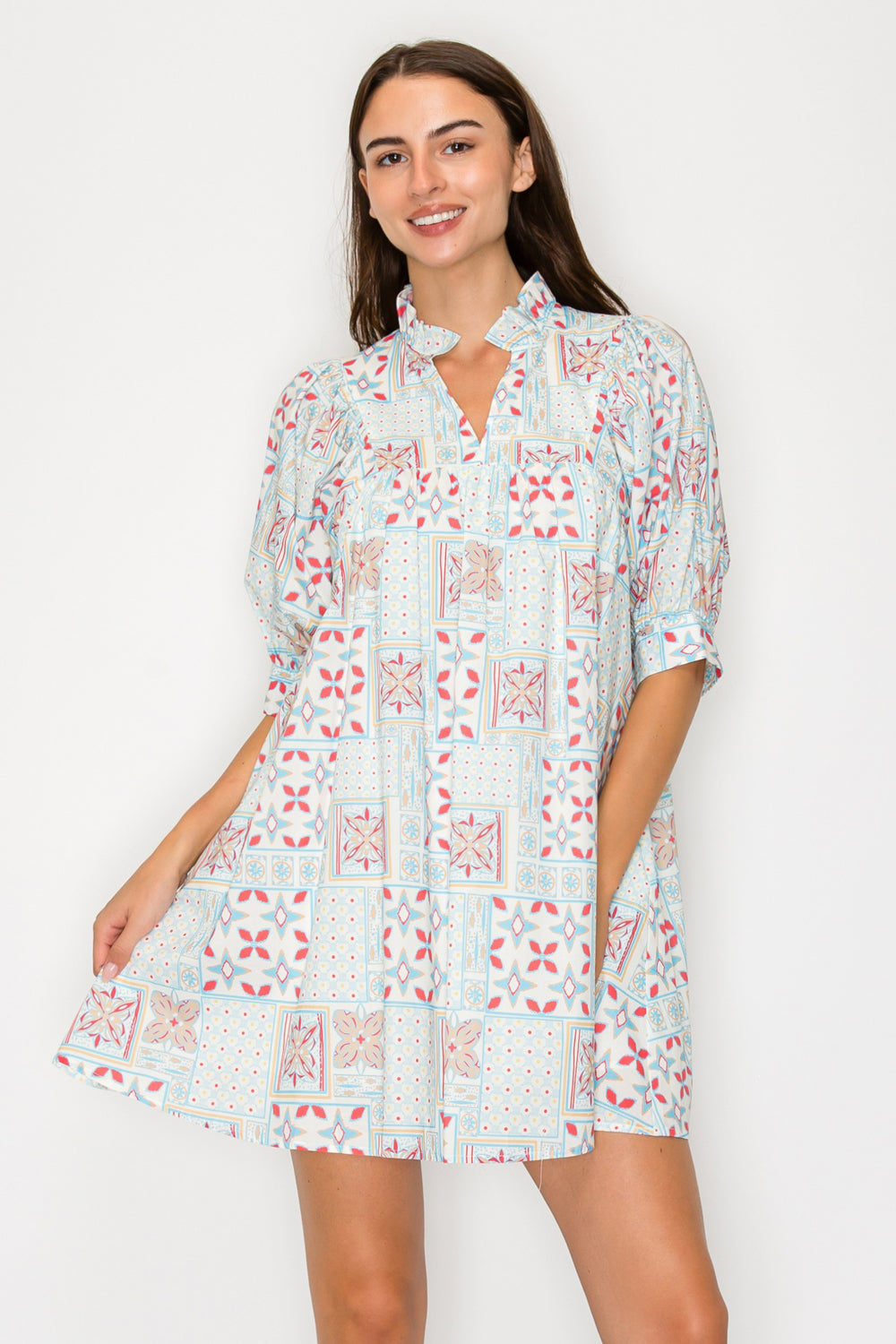 Front view of a model wearing the Rose Mandala Short Dress, a cream-colored geometric tile and star print babydoll mini dress with puff sleeves and a ruffled notched collar.