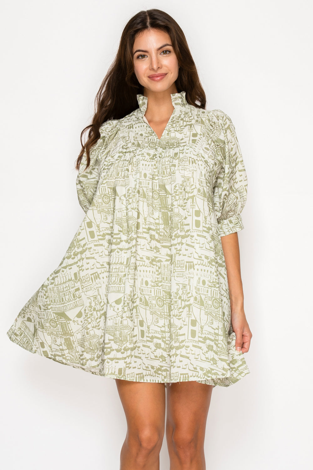 Model wearing the Verdant Bellezza Short Dress, a green and cream printed mini dress with a ruffle collar, puff sleeves, and a babydoll silhouette.