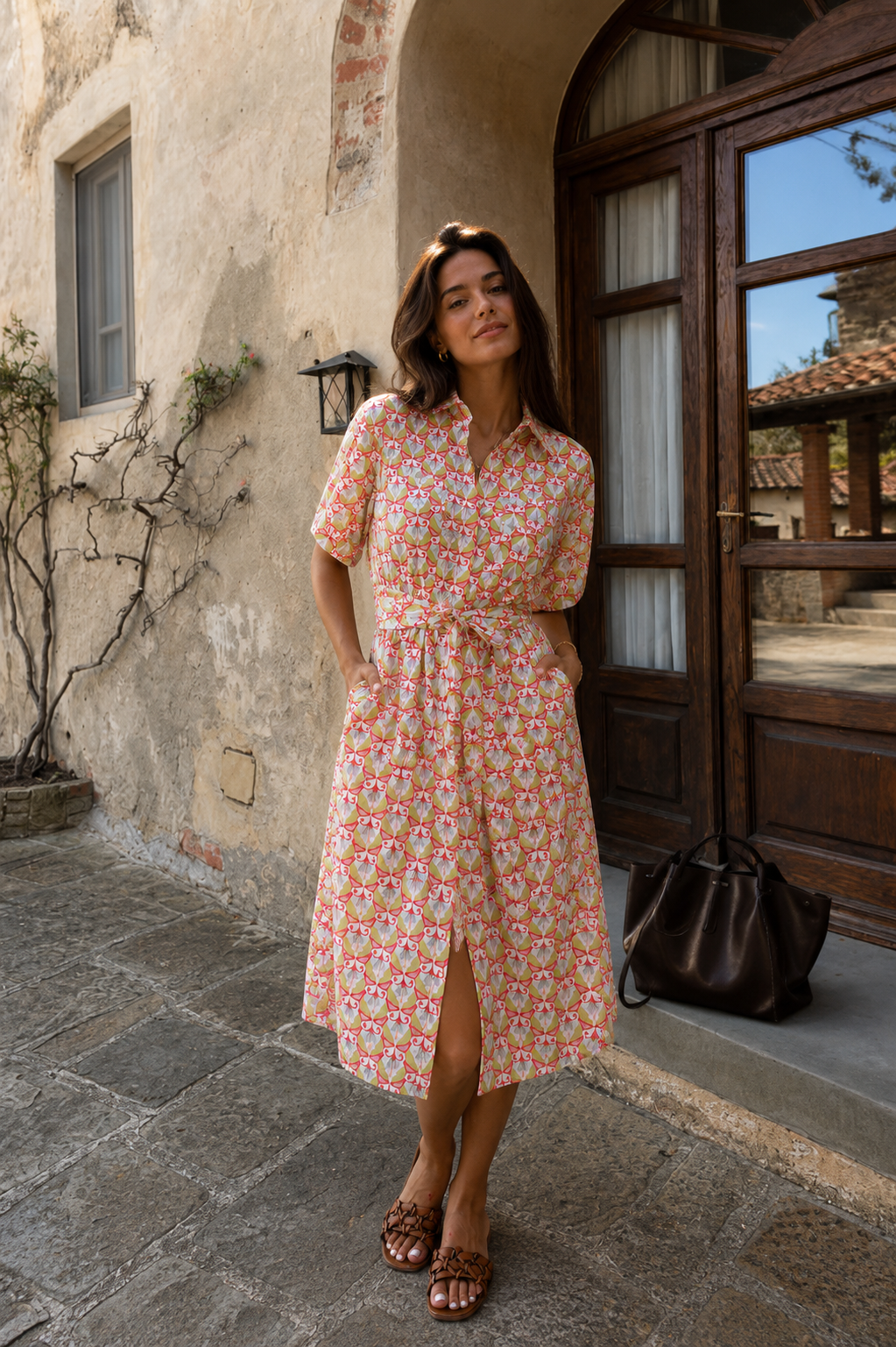 Woman in a floral dress standing in front of a rustic building entrance.