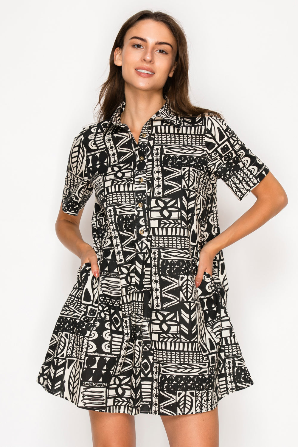 Model wearing the Nysas Ink Shirt Dress from Meet Me in Santorini, a black and white abstract print mini dress with a collar and short sleeves