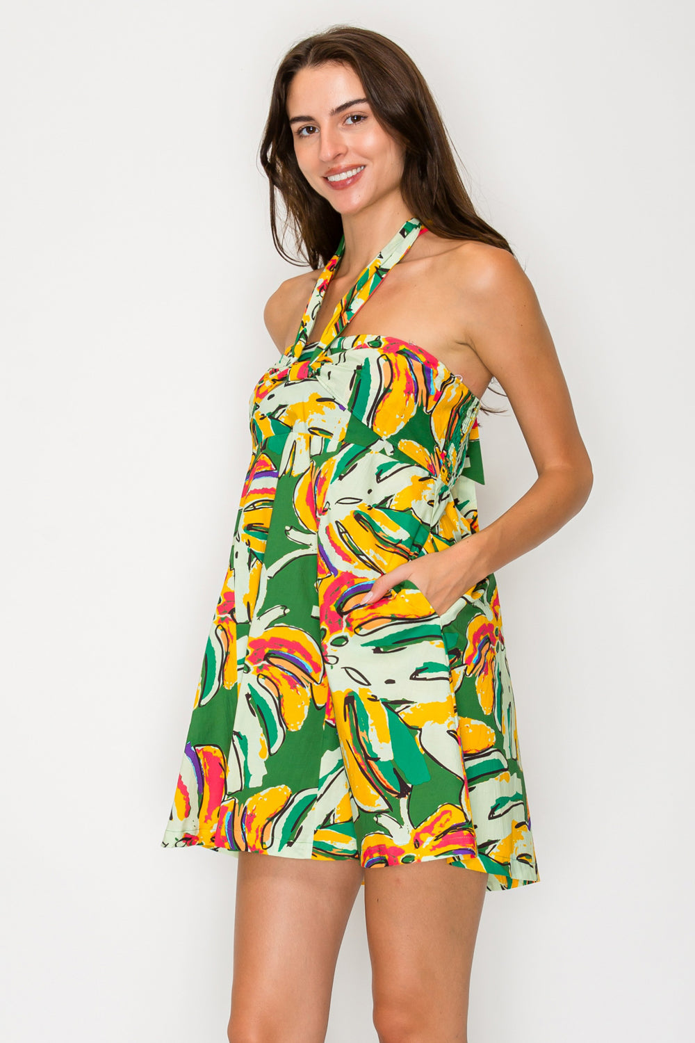 Woman wearing a colorful tropical print dress against a white background