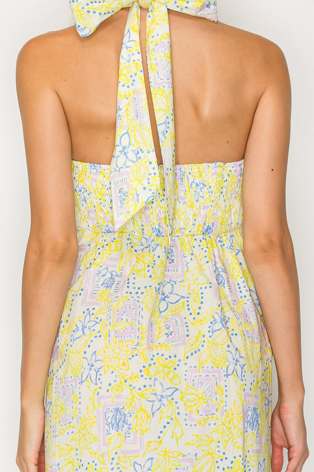 Yellow floral dress with a halter neck on a plain background