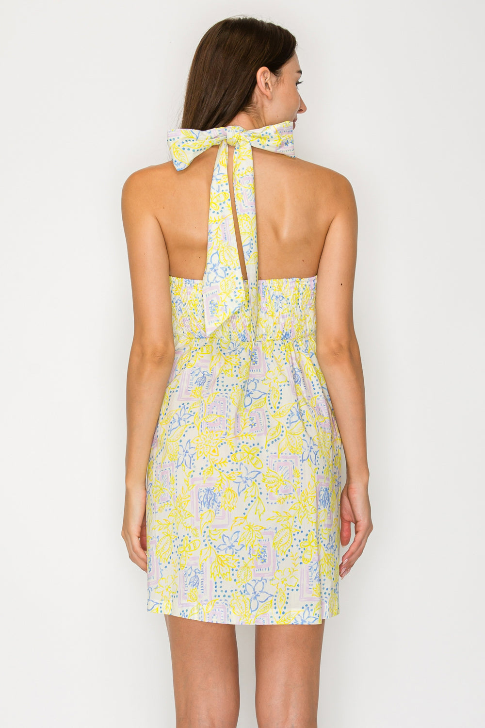 Woman wearing a yellow floral dress with a white background