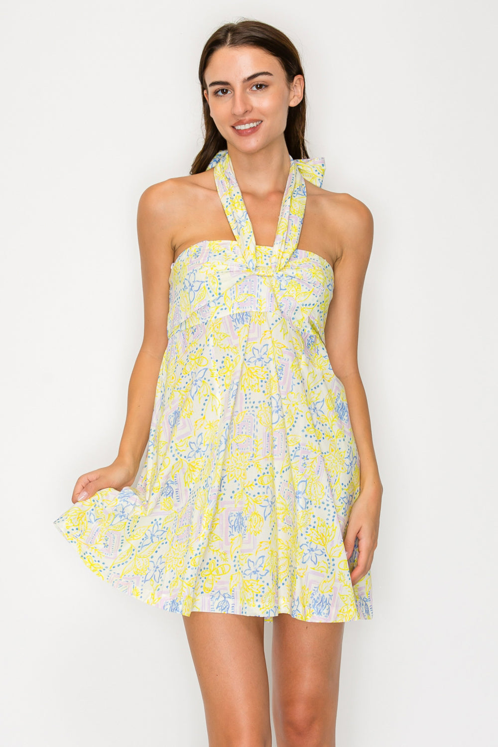 Woman wearing a yellow floral dress against a white background