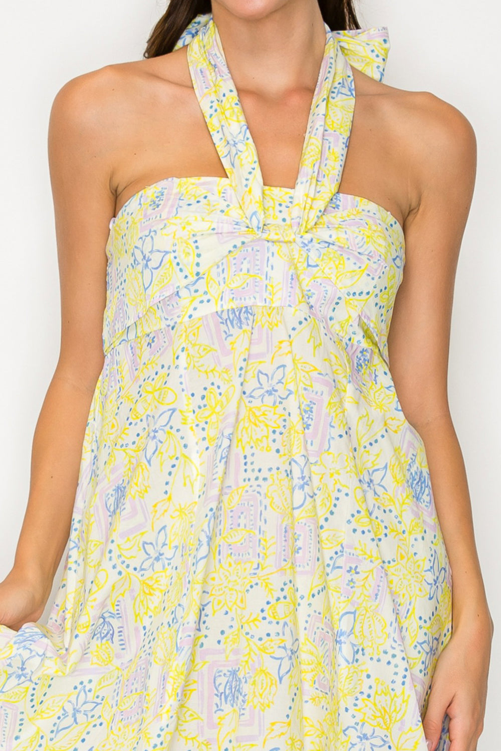 Woman wearing a yellow floral dress against a white background