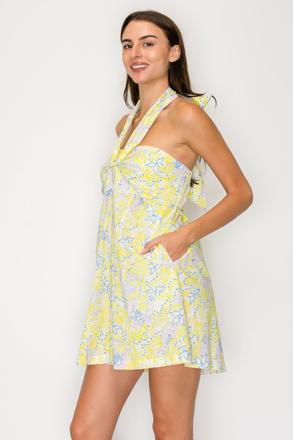 Woman wearing a yellow floral dress against a white background