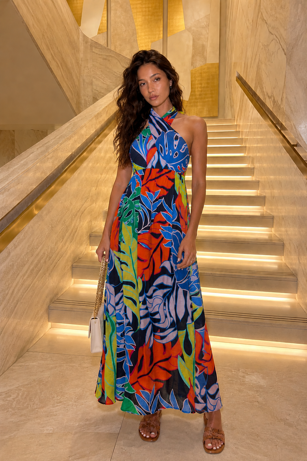 Woman in a colorful dress standing on a staircase in an elegant interior setting