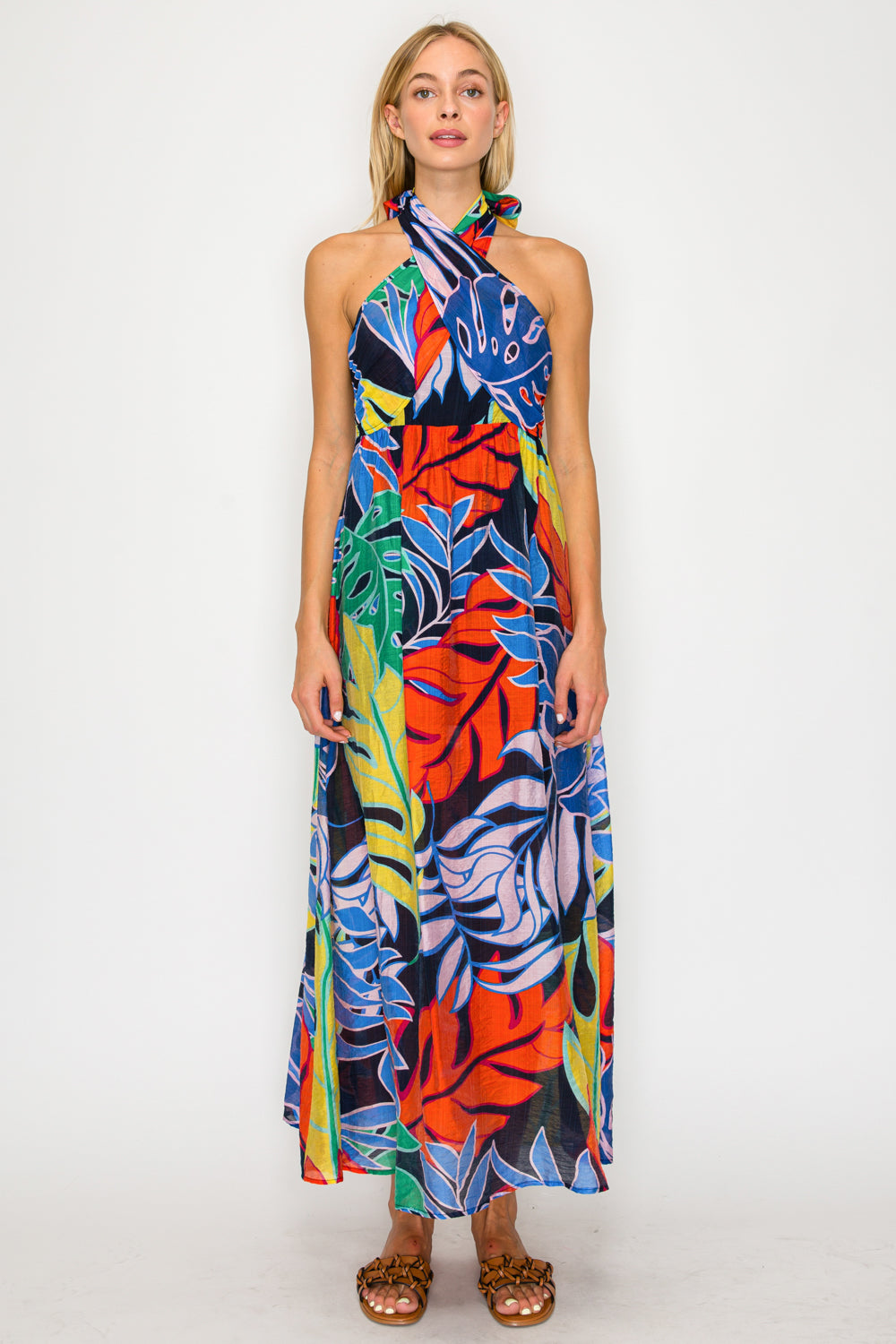 Woman wearing a colorful halter neck dress with a tropical leaf pattern on a white background