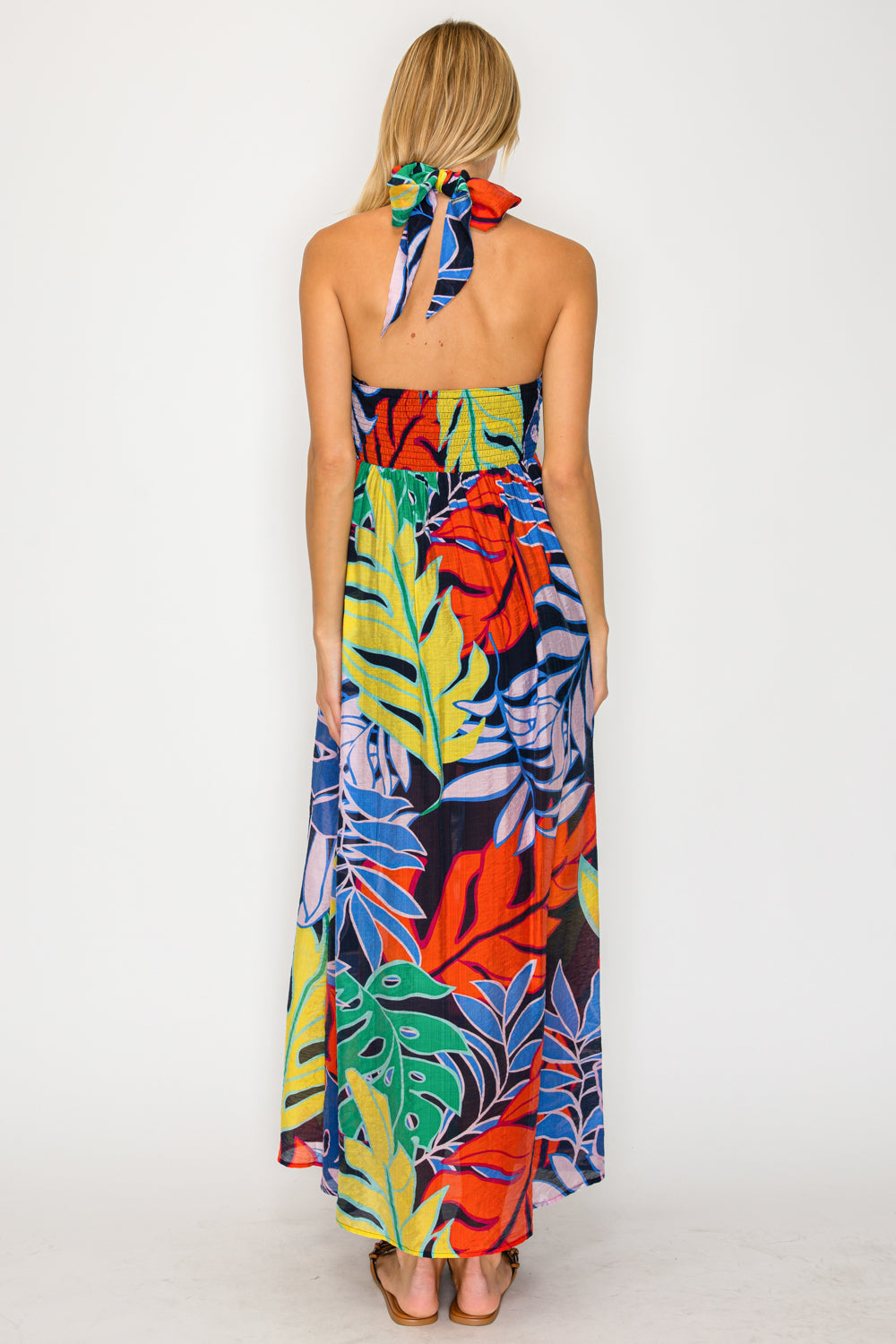 Woman wearing a colorful tropical leaf patterned dress on a white background