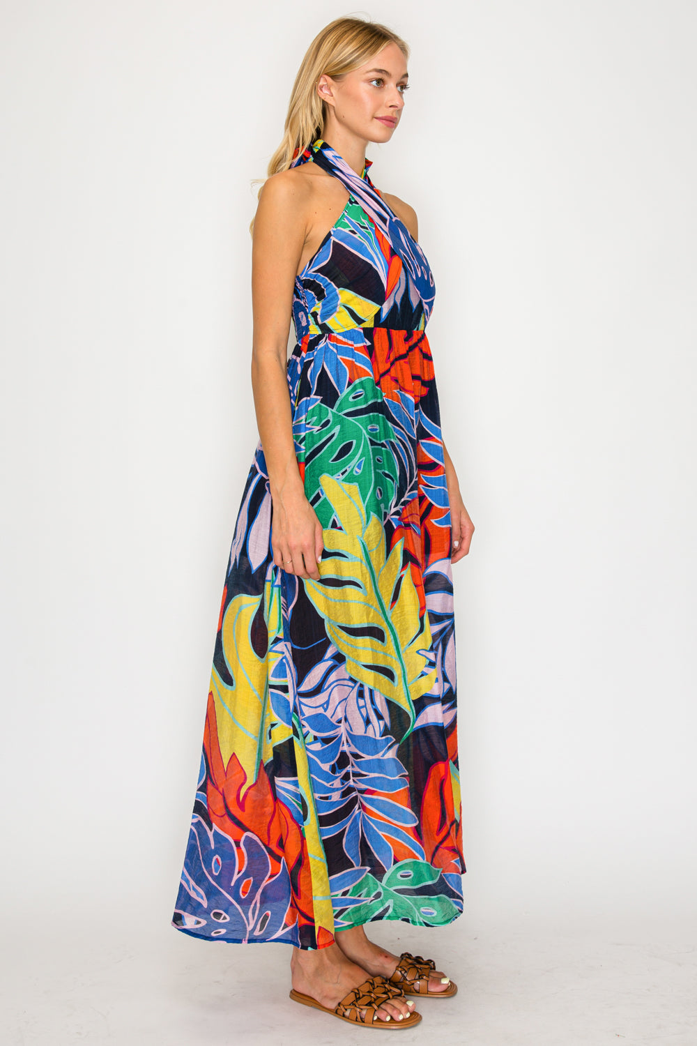 Woman wearing a colorful tropical print dress on a white background