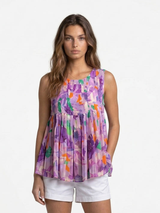 Model wearing the Lilac Dreamscape Pleats Top, a sleeveless pleated tunic featuring a vibrant purple, green, and orange abstract floral print.