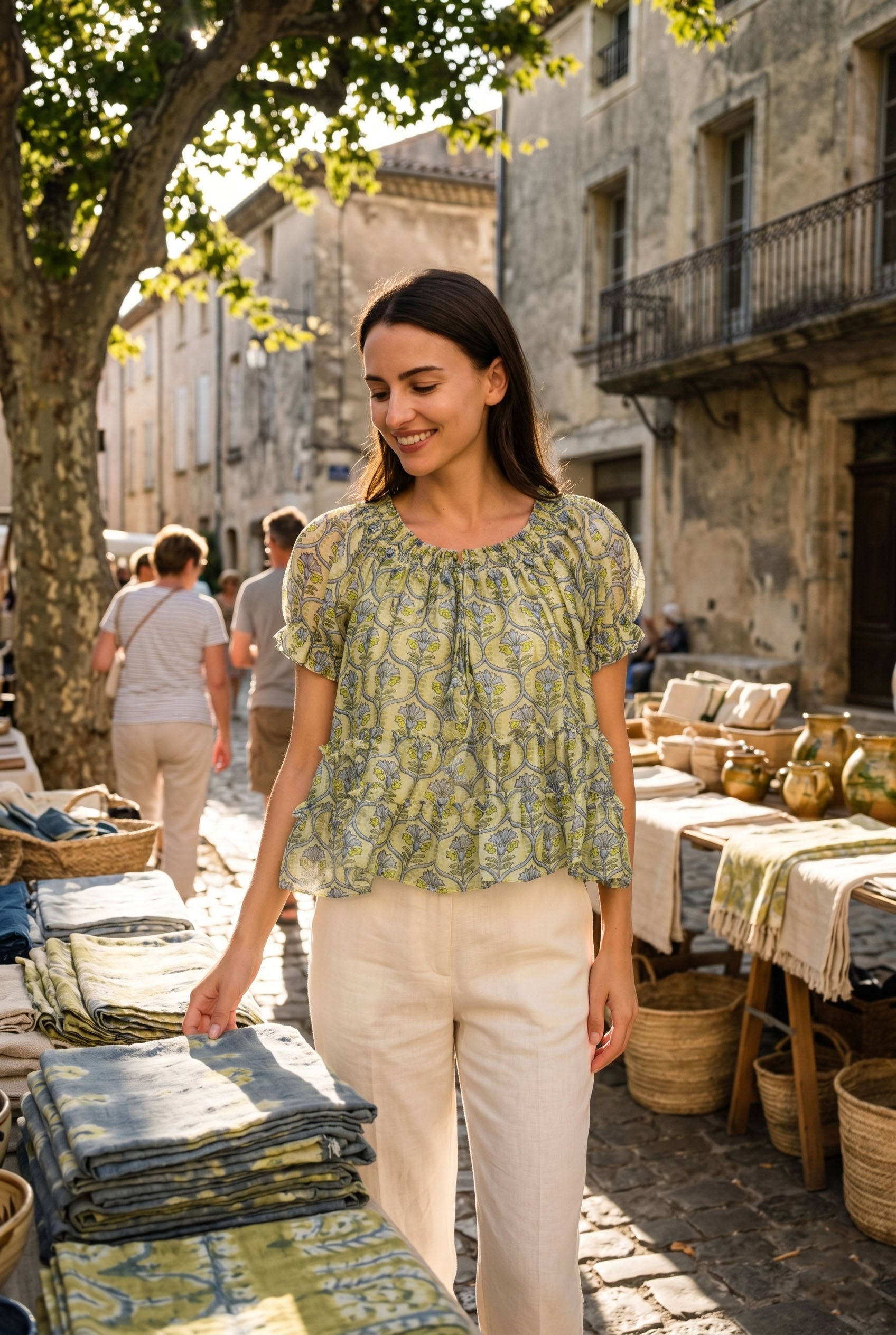 Woman in a green patterned blouse standing in an outdoor market setting.