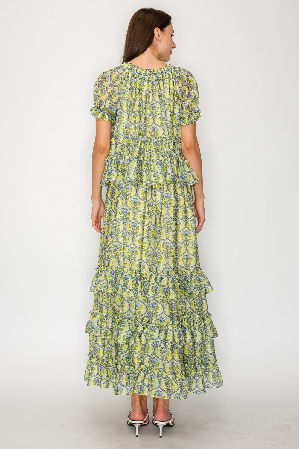Woman wearing a green and yellow floral dress on a white background